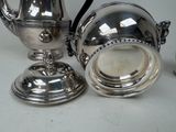 a silver tea pot and a silver cup on a table