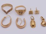 several gold rings and earrings on a white surface