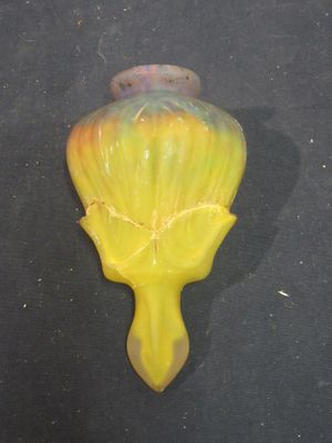 a yellow vase on a black surface with a black background