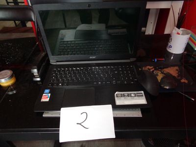 un ordinateur portable posé sur un bureau, sur lequel se trouve un bout de papier