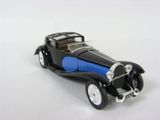une petite voiture jouet noire et bleue posée sur une surface blanche