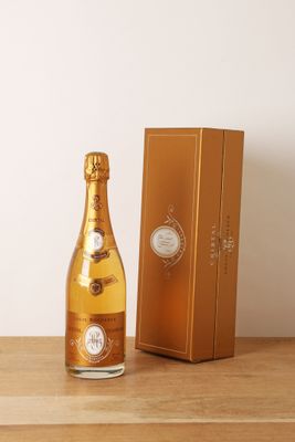une photo montrant une bouteille de champagne posée à côté d'une boîte sur une table