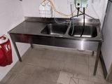 un lavabo dans des toilettes publiques, avec un sac rouge posé par terre