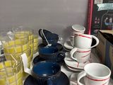 many cups and saucers on a shelf in a store