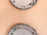 trois assiettes vertes et blanches ornées de motifs, posées sur une table
