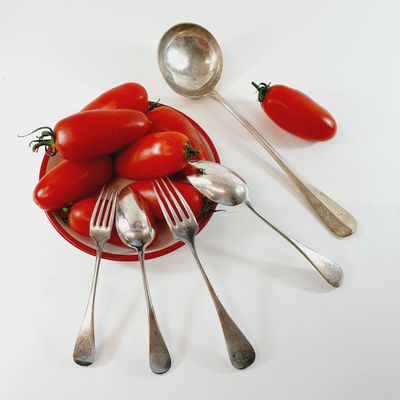 a bowl of tomatoes and spoons sitting on a table