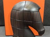 une sculpture en bois représentant une tête de cheval, exposée à côté d'une caisse orange