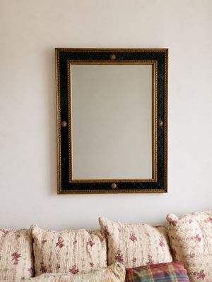 une photo d'un salon avec un canapé et un miroir accroché au mur