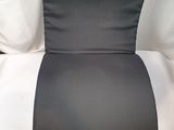 le dossier d'une chaise noire et blanche, sur lequel repose un coussin blanc