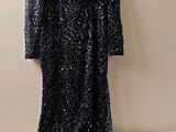 une robe noire à paillettes suspendue à un cintre accroché au mur