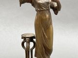 bronze statue of a woman holding a mirror and a stool