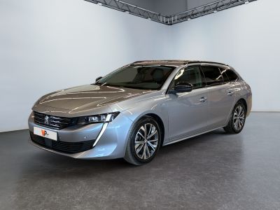 La voiture argentée est garée dans une grande pièce aux murs blancs.