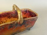 a red and gold bowl with a handle on it