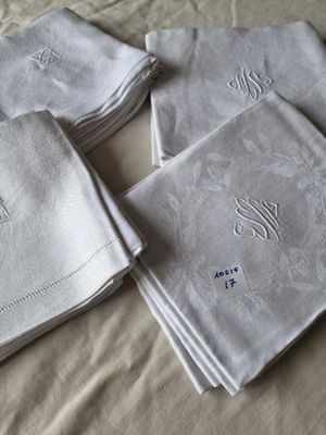 several folded napkins with embroidered monograms on them on a bed
