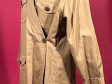 trench coat on a mannequin stand against a pink background
