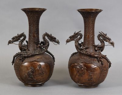une paire de vases en bronze ornés de têtes de dragon, posés sur une table