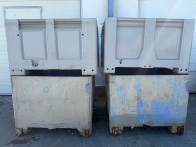 two trash bins sitting next to each other in front of a garage door
