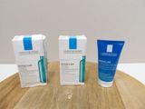 two tubes of cream and a tube of toothpaste sit on a wooden board