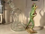 a frog figurine sitting on a shelf next to a glass bottle