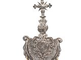 un plat en argent richement décoré, surmonté d'une croix