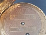 a gold pocket watch that is open on a blue surface