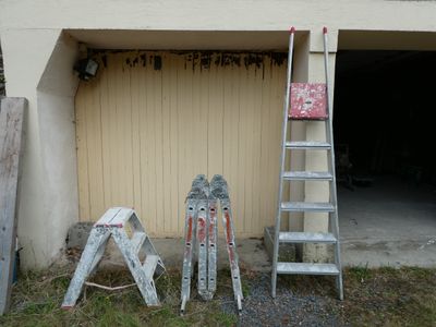 several ladders are leaning against a garage door and a ladder leaning against a garage door