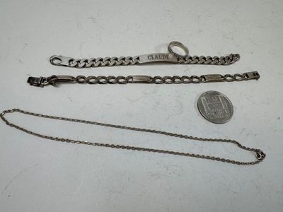 two silver bracelets and a coin on a white surface