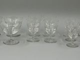 six wine glasses are lined up on a white surface