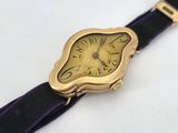 a gold watch with a purple band on a white surface