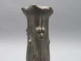 un vase en argent posé sur une table, sur fond gris