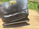 a person holding a black purse on top of a wooden table