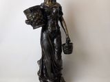 bronze statue of a woman holding a basket of flowers