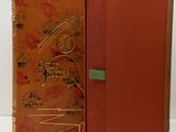 an old book with a red cover and a gold cover