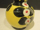 a yellow vase with black and white flowers on it