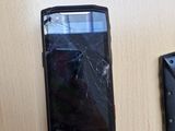 un téléphone portable cassé et un portefeuille abîmé posés sur une table