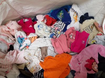 un tas de vêtements dans un sac en plastique posé par terre
