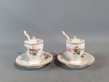 two cups and saucers with flowers on them sitting on a table