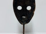a black mask on a metal stand on a white surface