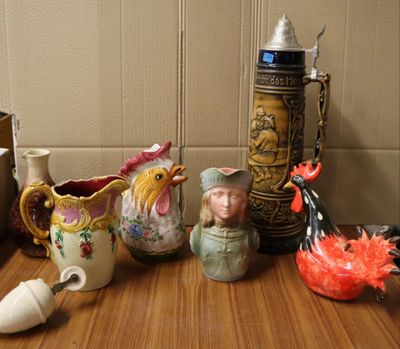de nombreux vases de toutes sortes posés sur une table, avec une horloge en arrière-plan