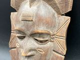 a close up of a wooden mask on a black background