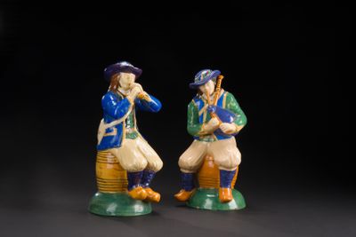 two figurines of two men sitting on top of each other