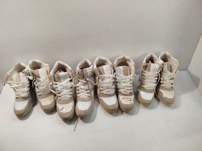 Plusieurs paires de chaussures sont alignées sur une surface blanche