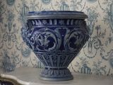 un vase bleu posé sur une table devant un papier peint