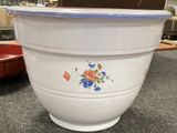 un grand saladier blanc orné de fleurs bleues et rouges