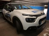 une Citroën blanche garée dans un parking couvert