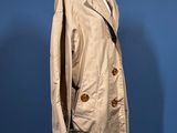 a beige trench coat on a mannequin stand against a blue background