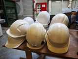 several hard hats sitting on top of a wooden table in a warehouse