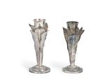 deux vases en argent posés l'un à côté de l'autre sur une surface blanche
