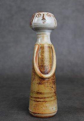 une petite figurine en céramique représentant un chat sur fond gris