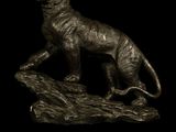 bronze statue of a cat on a rock on a black background